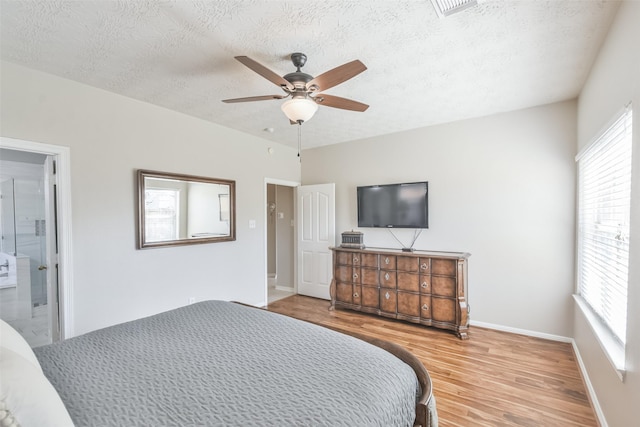 bedroom featuring wood-type flooring, a textured ceiling, ensuite bath, and ceiling fan