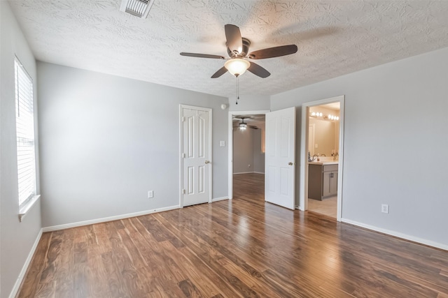 unfurnished bedroom featuring sink, ensuite bath, ceiling fan, dark hardwood / wood-style flooring, and a closet