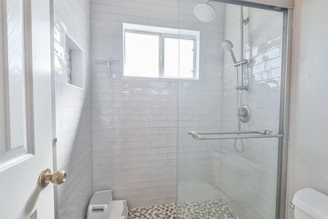 bathroom featuring a shower with door and toilet