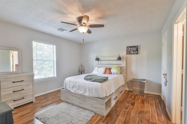 bedroom with ceiling fan, dark wood-type flooring, and a textured ceiling