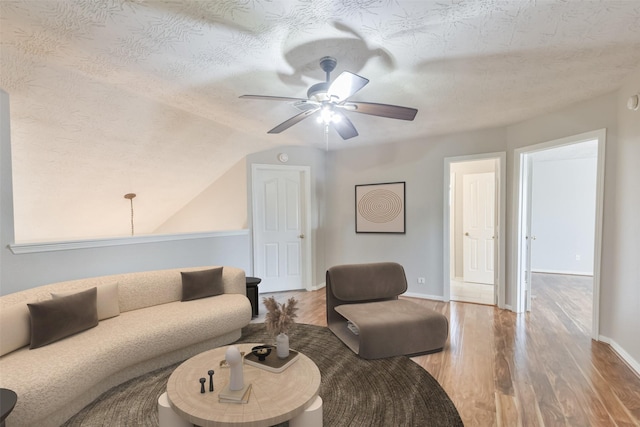 living room with hardwood / wood-style floors, ceiling fan, lofted ceiling, and a textured ceiling