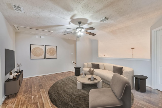 living room featuring a textured ceiling, hardwood / wood-style flooring, and ceiling fan