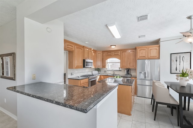 kitchen with sink, ceiling fan, appliances with stainless steel finishes, light tile patterned flooring, and kitchen peninsula