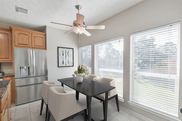 tiled dining area with a textured ceiling, plenty of natural light, and ceiling fan