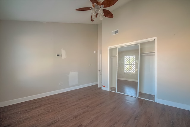 unfurnished bedroom featuring a closet, high vaulted ceiling, dark wood-type flooring, and ceiling fan