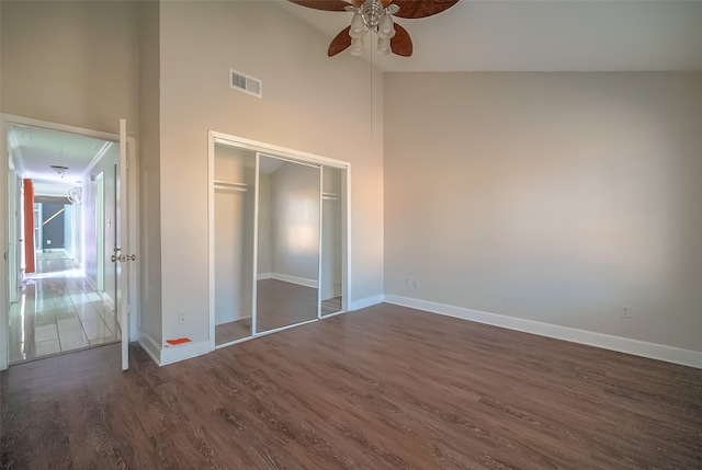 unfurnished bedroom with a closet, high vaulted ceiling, dark wood-type flooring, and ceiling fan