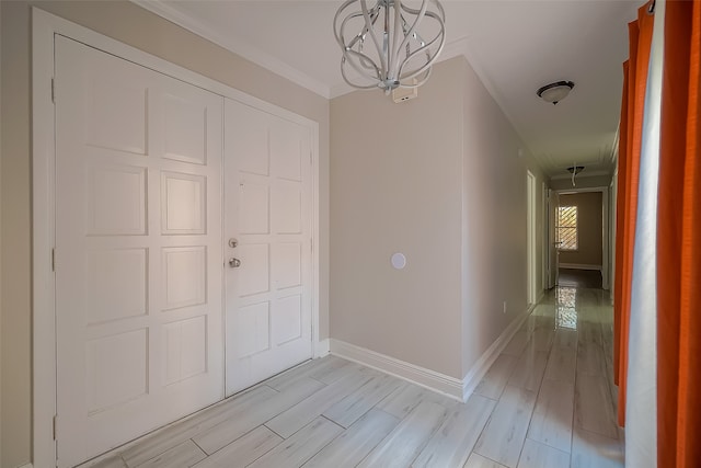 corridor featuring ornamental molding, light hardwood / wood-style flooring, and a chandelier