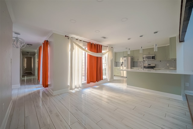 kitchen with kitchen peninsula, stainless steel appliances, crown molding, decorative backsplash, and light hardwood / wood-style flooring