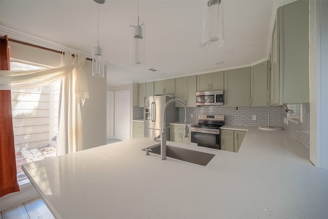 kitchen featuring appliances with stainless steel finishes, sink, green cabinetry, pendant lighting, and decorative backsplash