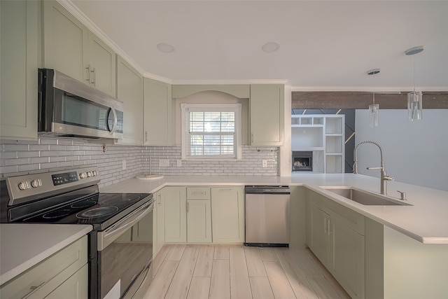 kitchen featuring tasteful backsplash, light wood-type flooring, sink, pendant lighting, and stainless steel appliances