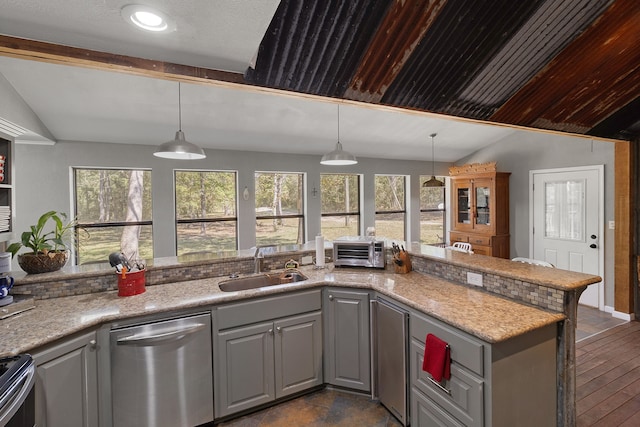 kitchen with lofted ceiling, gray cabinetry, stainless steel appliances, and hanging light fixtures