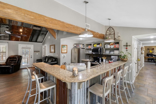 kitchen featuring vaulted ceiling with beams, pendant lighting, a kitchen breakfast bar, and stainless steel appliances