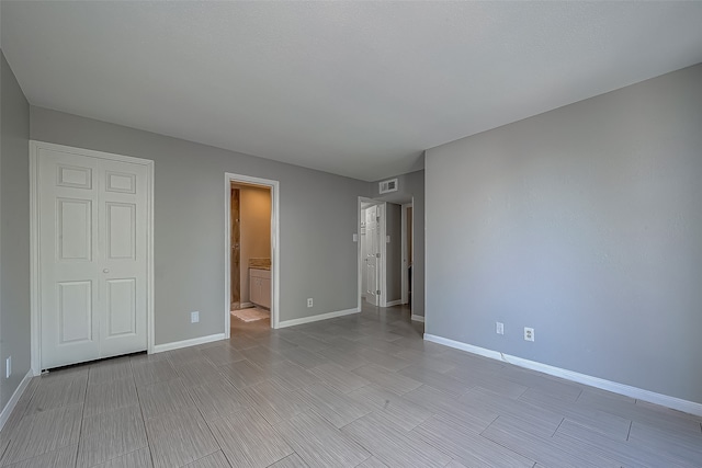 unfurnished bedroom featuring ensuite bathroom and a closet