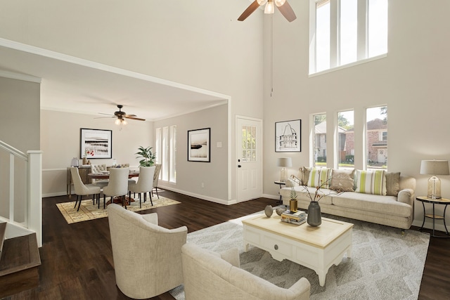 living room featuring ornamental molding, ceiling fan, a towering ceiling, and dark hardwood / wood-style flooring