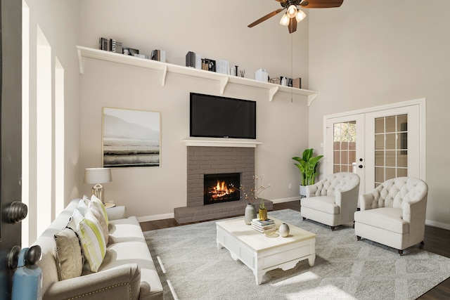 living room with a fireplace, french doors, ceiling fan, a high ceiling, and hardwood / wood-style flooring