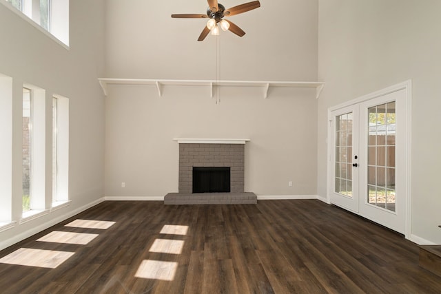 unfurnished living room featuring dark wood-type flooring, a towering ceiling, french doors, and a fireplace