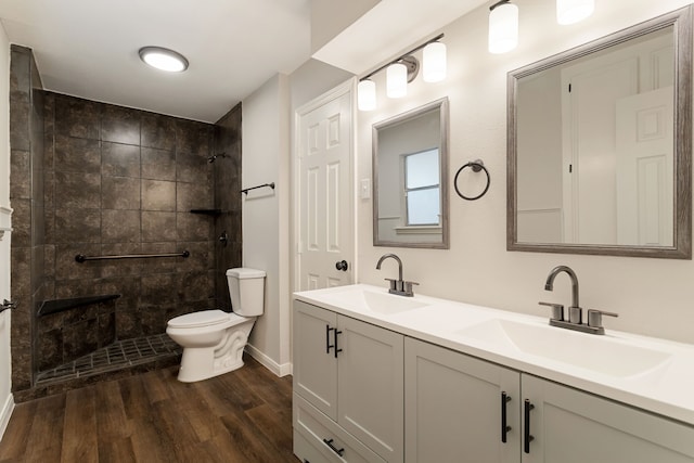 bathroom featuring toilet, hardwood / wood-style flooring, vanity, and tiled shower