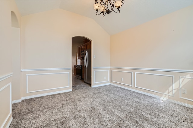 empty room featuring a chandelier, vaulted ceiling, and carpet flooring