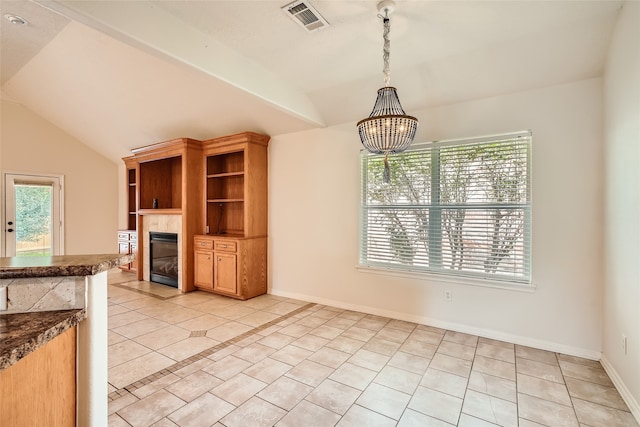 kitchen featuring light tile patterned floors, a healthy amount of sunlight, vaulted ceiling, and a fireplace