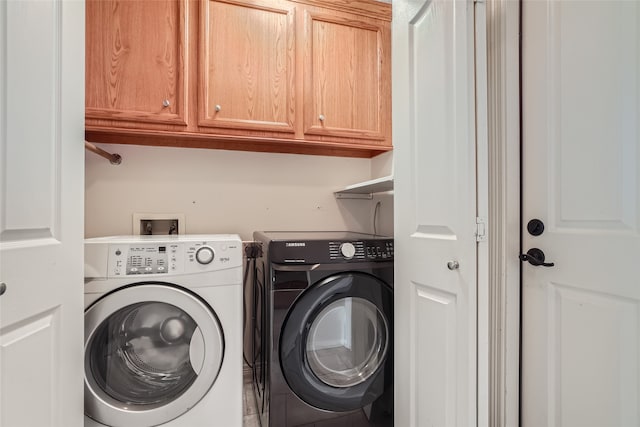 clothes washing area with cabinets and washer and clothes dryer