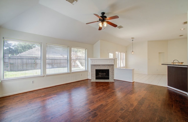 unfurnished living room featuring a healthy amount of sunlight, wood-type flooring, and a tile fireplace