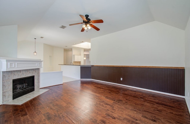 unfurnished living room featuring lofted ceiling, dark hardwood / wood-style floors, a fireplace, and ceiling fan