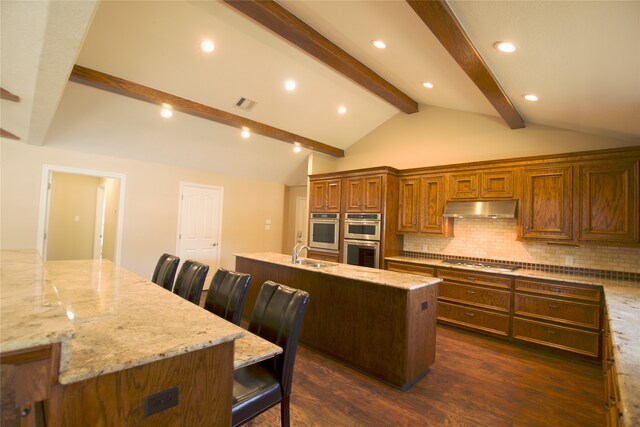 kitchen with sink, backsplash, stainless steel appliances, a spacious island, and light stone counters