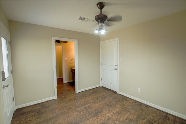 unfurnished bedroom featuring dark wood-type flooring, ceiling fan, and ensuite bath