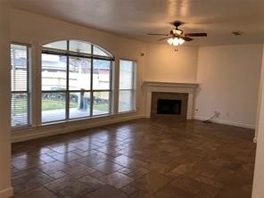 unfurnished living room featuring a wealth of natural light and ceiling fan