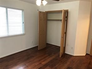 unfurnished bedroom featuring dark wood-type flooring, ceiling fan, and a closet