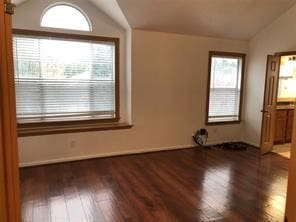 unfurnished room with dark wood-type flooring and vaulted ceiling