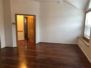 unfurnished room featuring dark hardwood / wood-style flooring, lofted ceiling, and a wealth of natural light