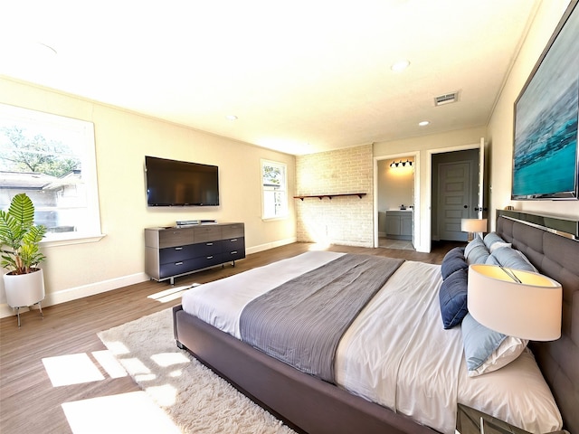 bedroom with ensuite bath and wood-type flooring