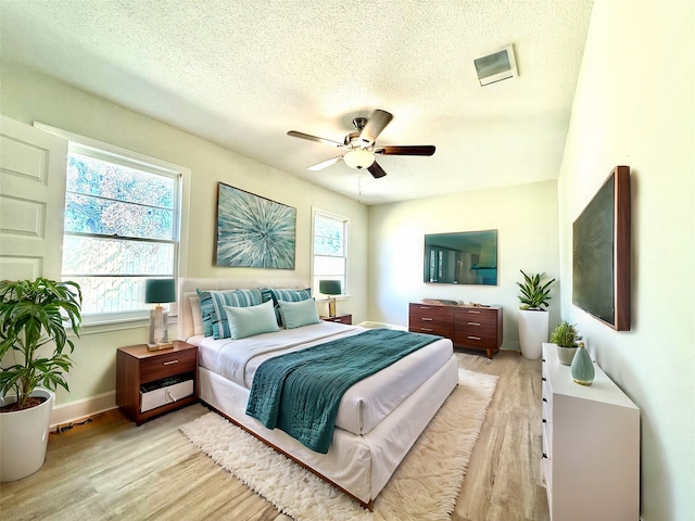 bedroom featuring light hardwood / wood-style floors, a textured ceiling, and ceiling fan