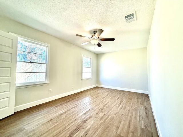 spare room with a textured ceiling, light wood-type flooring, and ceiling fan