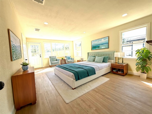 bedroom featuring a textured ceiling, multiple windows, and light wood-type flooring