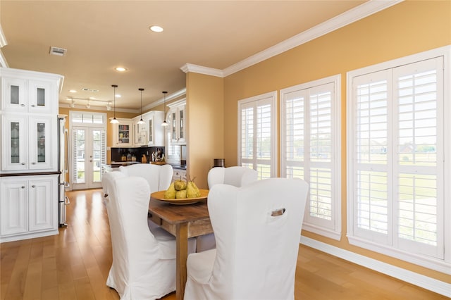 dining room featuring french doors, crown molding, and light hardwood / wood-style floors