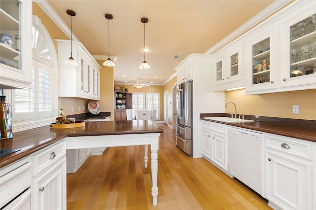 kitchen featuring stainless steel fridge, white dishwasher, light wood-type flooring, sink, and decorative light fixtures