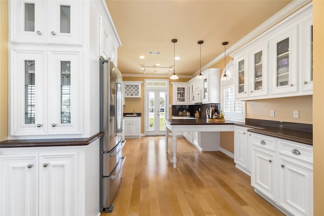 kitchen with stainless steel fridge, crown molding, pendant lighting, light wood-type flooring, and white cabinetry