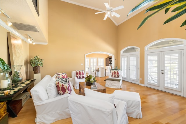 living room featuring ceiling fan, high vaulted ceiling, light wood-type flooring, crown molding, and french doors