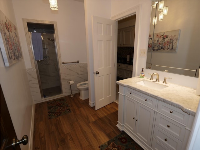 bathroom with wood-type flooring, toilet, a shower with door, vanity, and tile walls