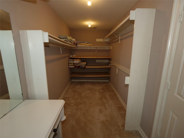 walk in closet featuring dark colored carpet