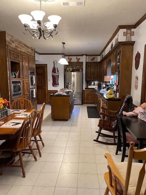 kitchen featuring a center island, hanging light fixtures, a chandelier, appliances with stainless steel finishes, and ornamental molding