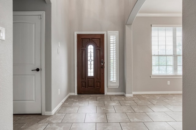 entryway with ornamental molding and light tile patterned flooring