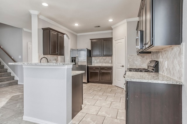 kitchen with crown molding, light stone counters, stainless steel appliances, and backsplash