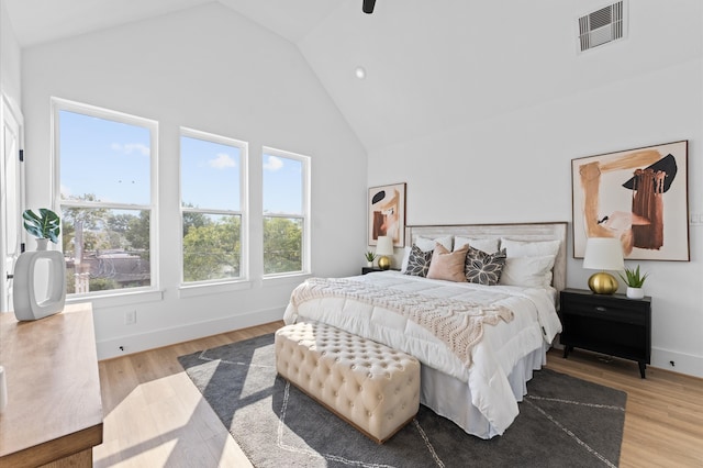 bedroom featuring multiple windows, light hardwood / wood-style flooring, and high vaulted ceiling