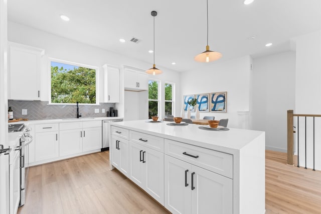 kitchen featuring pendant lighting, light wood-type flooring, white cabinetry, and appliances with stainless steel finishes