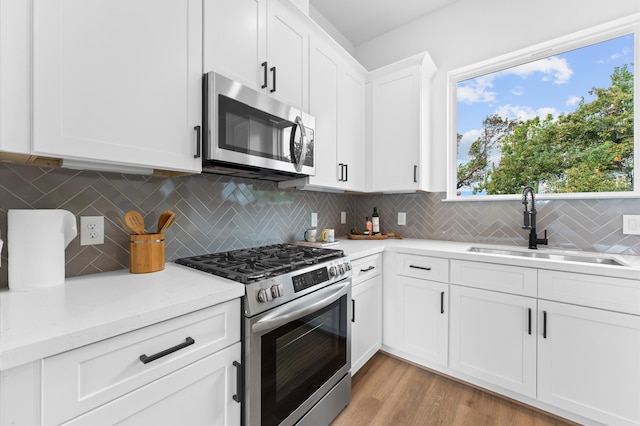 kitchen with decorative backsplash, stainless steel appliances, sink, light hardwood / wood-style flooring, and white cabinets