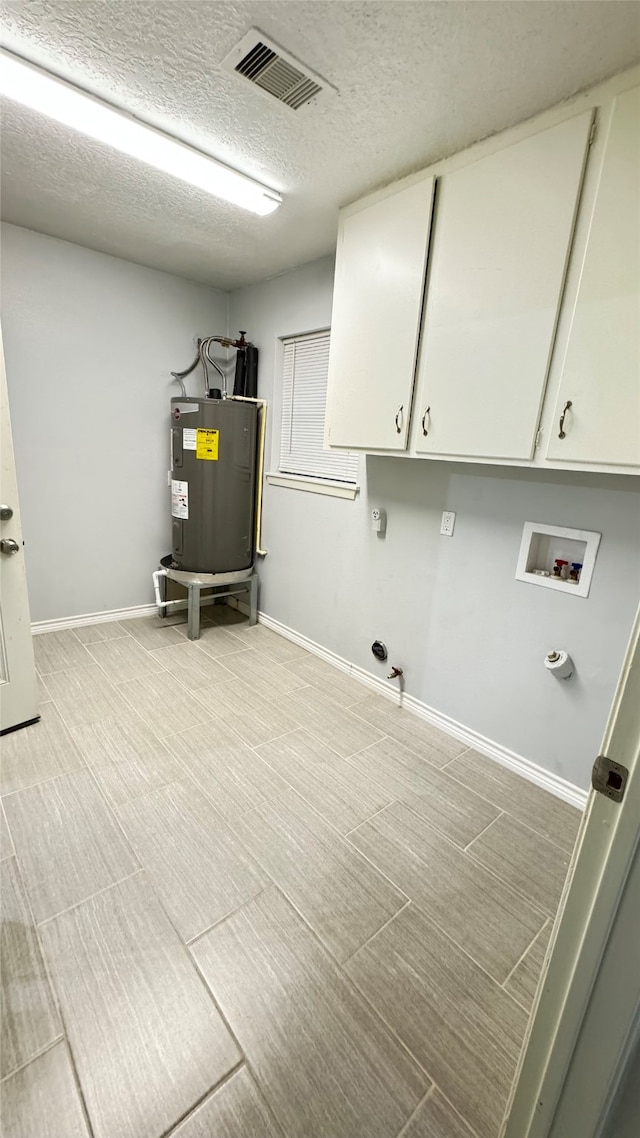 laundry room with hookup for a washing machine, a textured ceiling, gas dryer hookup, water heater, and cabinets