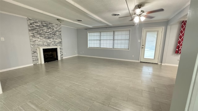 unfurnished living room with beamed ceiling, ornamental molding, a large fireplace, and ceiling fan